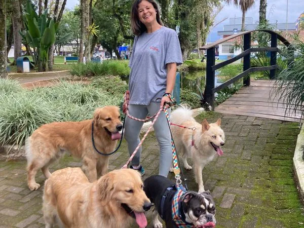 Profissional do Espaço CatDog passeando com cães em praça de Ubatuba